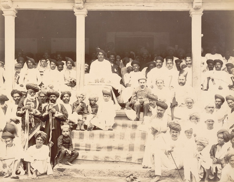 Photograph of the Maharaja of Kolhapur watching a Wrestling match with his Officers in crowd